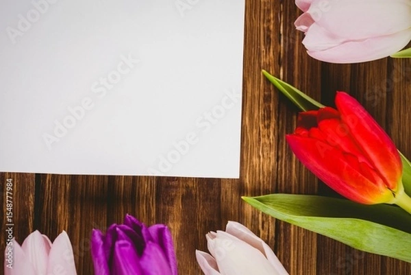 Obraz Blank white sheet is lying on dark brown wooden table in flat design, featuring tulip border