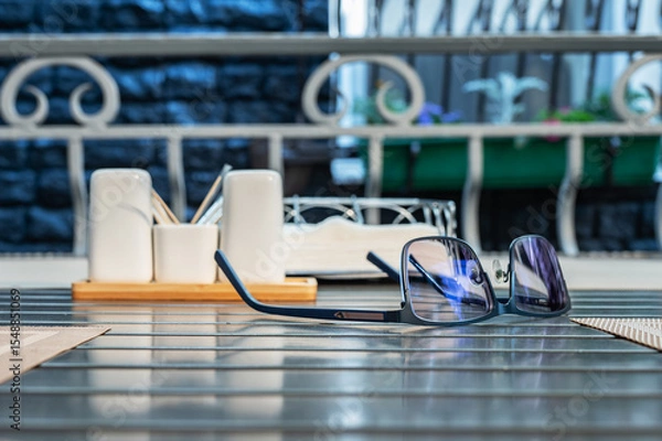 Fototapeta Eyeglasses lie on table in a street cafe.