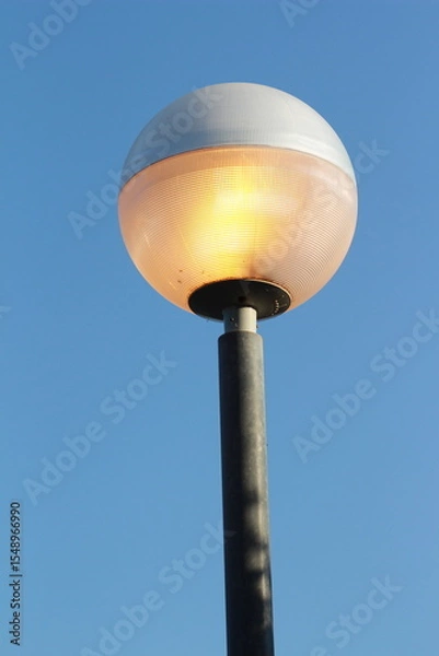 Obraz street lamp on blue sky. one night lamp post shines with a faint light on a blue background 