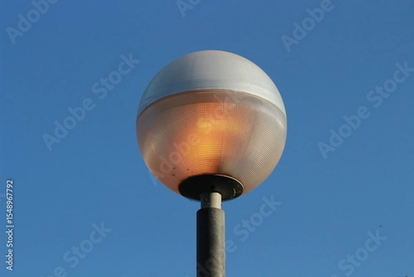 Obraz street lamp on blue sky. one night lamp post shines with a faint light on a blue background 
