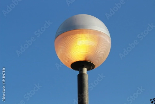 Obraz street lamp on blue sky. one night lamp post shines with a faint light on a blue background 