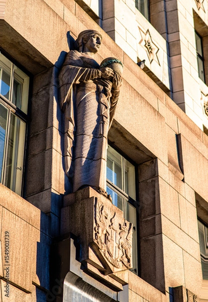 Obraz Elegant stone statue holding a globe on the façade of the South Africa House in Trafalgar Square, London. A symbol of international presence and diplomacy, captured in warm sunlight.