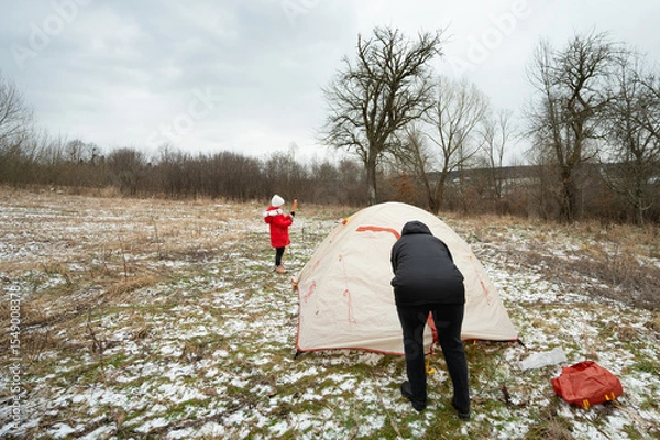 Fototapeta On a brisk day filled with outdoor adventure, we find ourselves setting up a warm and inviting tent in the midst of a snow covered meadow, enjoying quality time with family