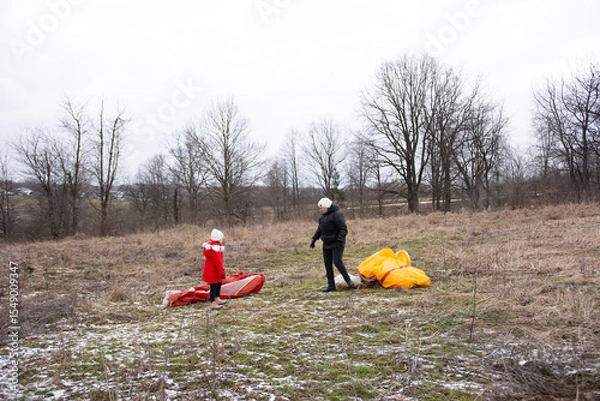 Fototapeta Family bonding while preparing colorful kites in a winter field, capturing the essence of outdoor fun and creativity