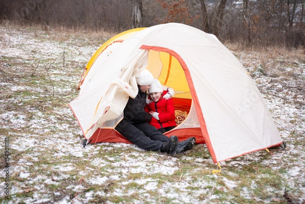 Fototapeta Winter camping adventure captured in a cozy tent with joyful children sharing warm moments in the snowy landscape during a chilly day