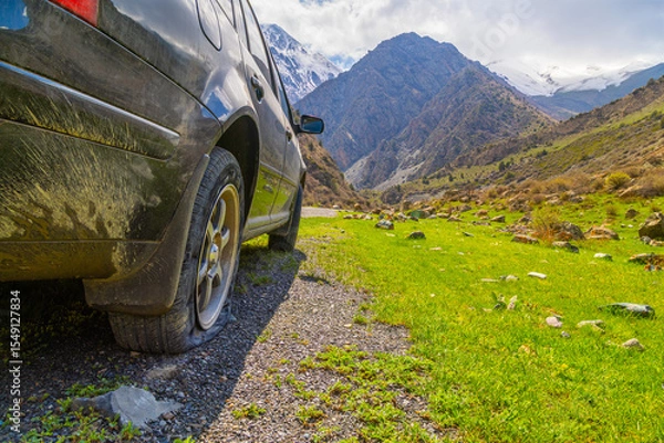 Obraz Car with flat tire in serene mountainous region in Kyrgyzstan