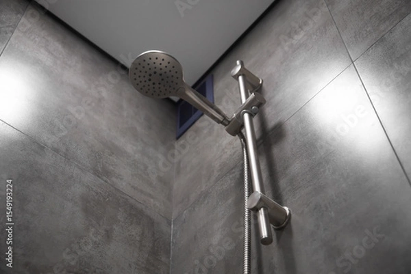 Obraz Close-up of a shower head hanging on a rail in a modern bathroom, showcasing sleek design and functionality within a clean and contemporary setting
