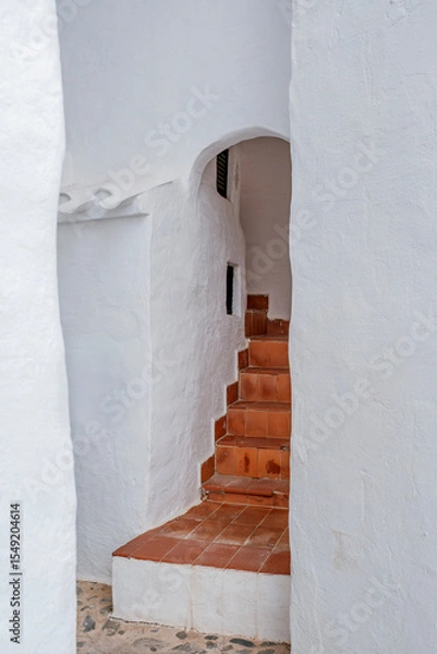 Fototapeta Curved Terracotta Staircase Within Whitewashed Archway in Binibeca Vell. Menorcan Architecture, Hidden Alley, Traditional Mediterranean Design