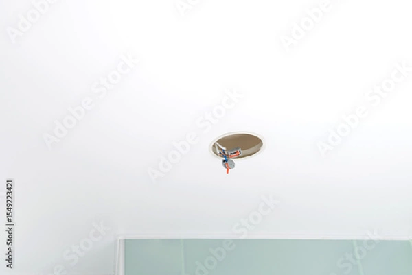 Fototapeta white stretch ceiling with a hole for lighting, with faulty wiring in the hole