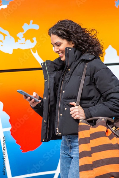 Obraz Travel woman smiling while looking at her phone