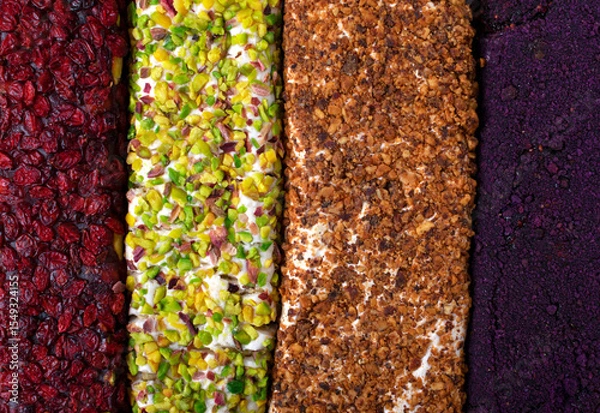 Fototapeta Turkish delight rolls with dried cranberries, pistachios, roasted hazelnuts and freeze dried berry powder. Texture close-up, top view