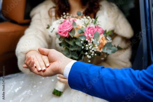 Obraz Close-up of groom helping bride step down, hands touching and bouquet in focus. Intimate wedding moment captured without showing faces. Symbol of support, love, and togetherness.