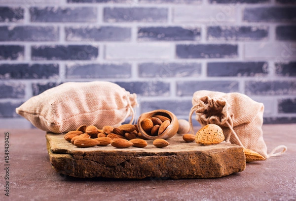 Obraz Fragrant roasted almonds with kitchen utensils on a stone table