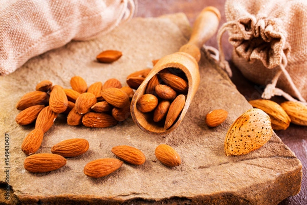 Obraz Fragrant roasted almonds with kitchen utensils on a stone table