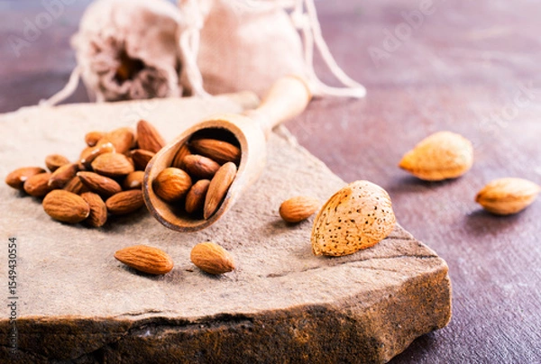 Obraz Fragrant roasted almonds with kitchen utensils on a stone table