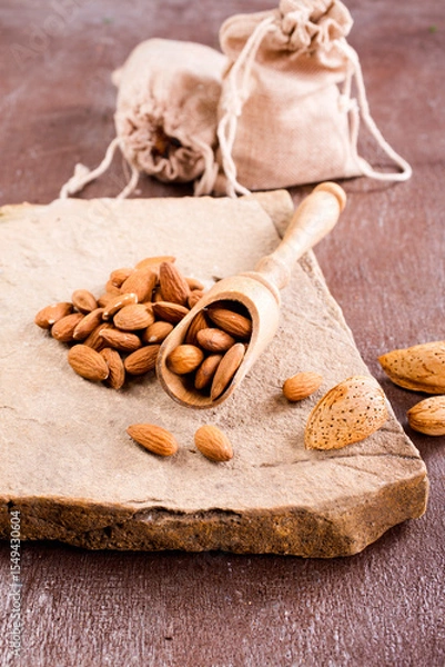 Obraz Fragrant roasted almonds with kitchen utensils on a stone table