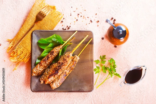 Obraz Grilled Lula kebab on skewers with spices in a claim plate on a table