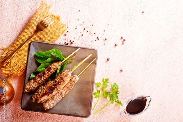 Obraz Grilled Lula kebab on skewers with spices in a claim plate on a table