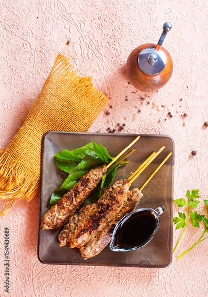 Obraz Grilled Lula kebab on skewers with spices in a claim plate on a table