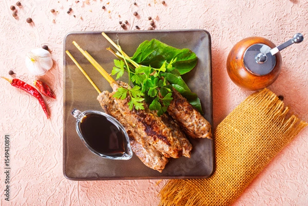 Obraz Grilled Lula kebab on skewers with spices in a claim plate on a table