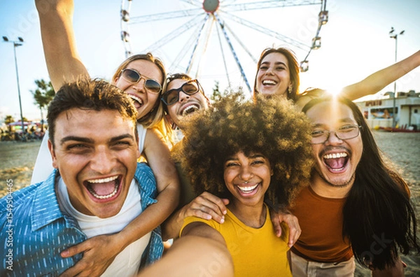 Fototapeta Multiracial group of friends taking selfie with smart mobile phone outside - Happy young people having fun in front of ferris wheel at summer vacation - Technology and summertime holidays concept