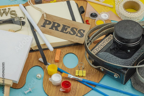 Obraz Flat lay of press badge, vintage camera, art supplies, notebook, and exhibition label