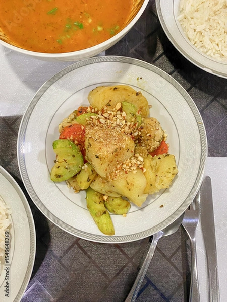 Fototapeta Top angle vertical shot of Paraguayan cuisine panache de verduras (mixed vegetable dish) on dining table, surrounded with vegetable soup and rice. The dish is a blend of Guarani and Spanish Influence.