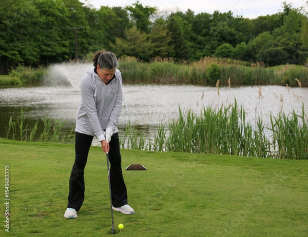 Obraz Golf Practice Session by the Serene Pond in a Lush Park Setting