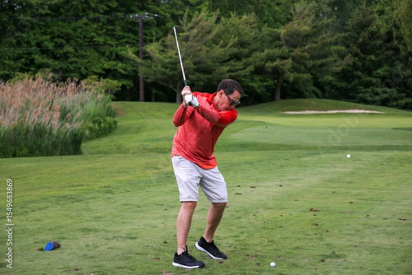 Obraz Golfer Swings Club on a Sunny Day at a Lush Green Golf Course