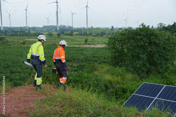 Fototapeta Solar energy engineers work on consulting and monitoring the efficiency of wind turbines.