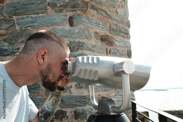 Obraz A man observing the Danube from Ram Fortress through a public binocular viewer. A popular tourist destination in Serbia country.