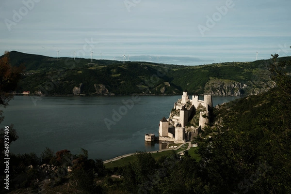Obraz Elevated view of Golubac Fortress on the Danube, surrounded by lush green hills and blue sky. A popular tourist destination