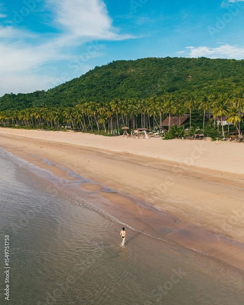 Obraz Bird's eye top aerial view of woman relaxing in sandy beach in the pristine turquoise shoreline and sweeping coastal landscape of Nacpan Beach in El Nido, Palawan, Philippines