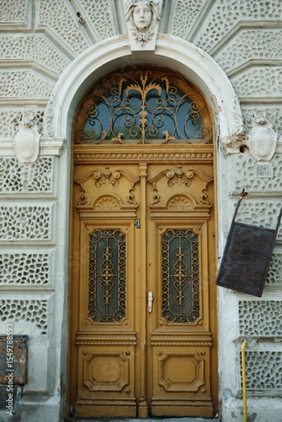 Obraz Vintage carved wooden door with decorative wrought iron and architectural details, located in Vrsac town, Serbia. Historical charm and intricate craftsmanship.