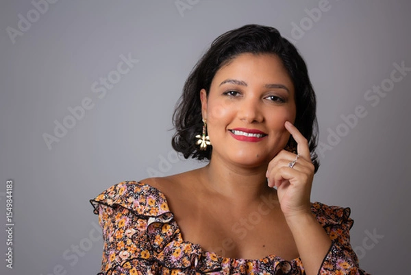 Fototapeta Beautiful short hair woman smiling with hand on her face. Perfect for friendly and happy concepts, femininity and beauty. Horizontal studio portrait with copy space on gray background.