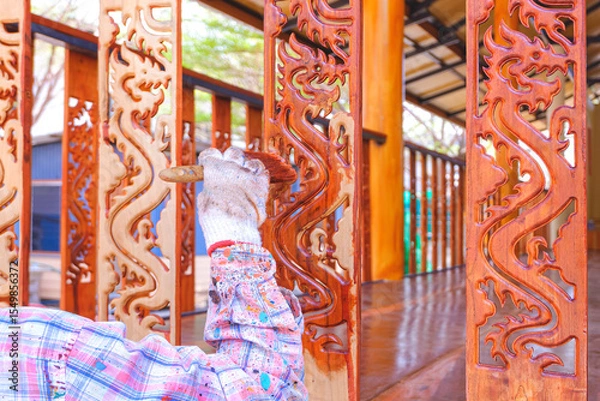Fototapeta Painter hand is applying a coat of shellac to the wooden baluster on porch area of vintage house, close up with copy space