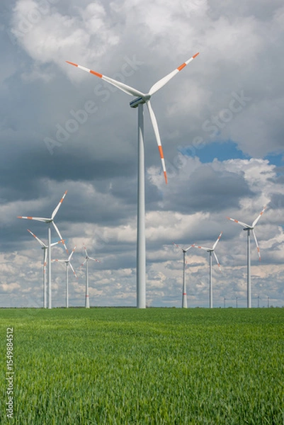 Fototapeta Cover page with beautiful green farm landscape with light and shadow waves in Germany with clouds in sky, and wind turbines to generate electrical power.