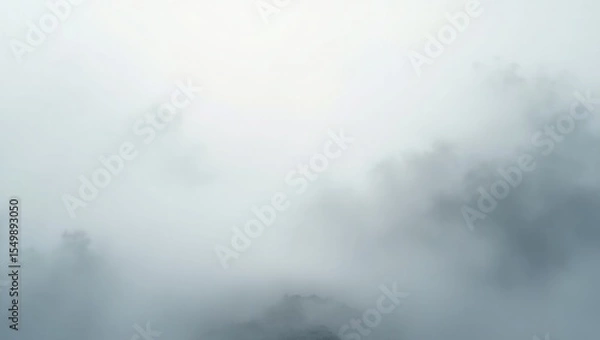Fototapeta Misty mountain peaks emerge from thick fog with a bright sky above creating an ethereal and atmospheric landscape scene
