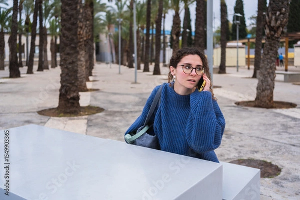 Fototapeta University student making an important phone call while studying outdoors in a park