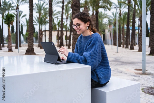 Fototapeta University student using digital tablet and stylus, enjoying outdoor learning in urban park