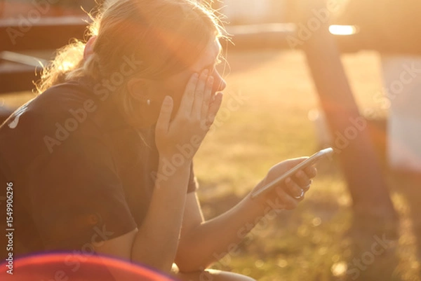Obraz Cyber bullying and online harassment: A teen girl crying with a phone in hand, symbolizing the danger and emotional violence of the internet