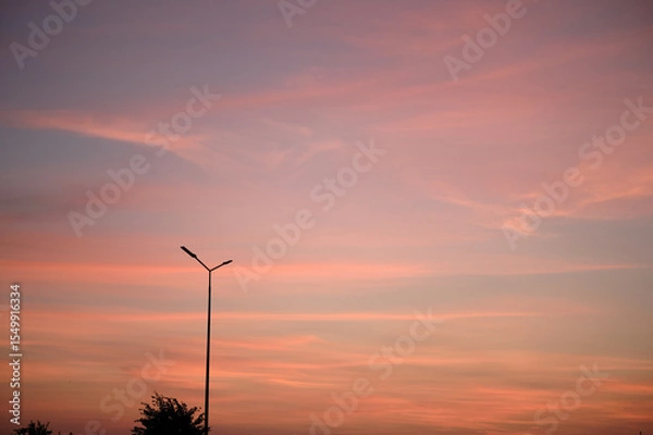 Fototapeta Street lantern on the background of a colorful sky during sunset. Romantic atmosphere in the evening