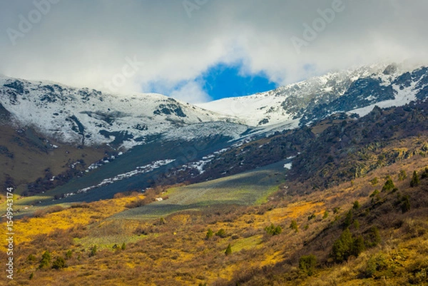 Obraz Majestic snow-covered mountains with rocks and trees in Kyrgyzstan