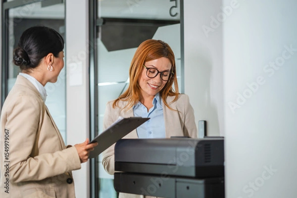 Obraz two multicultural female colleague stand in office by the copy machine