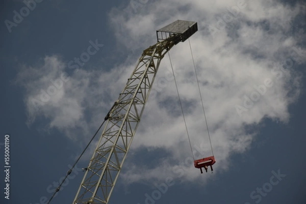 Obraz crane with hanging cables seen from below with a partially cloudy sky in the background 