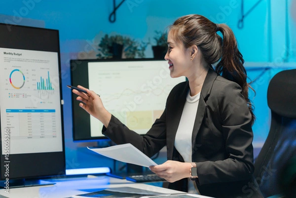 Obraz Businesswoman Analyzing Financial Data on Computer Screens