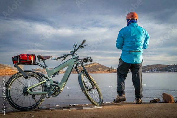 Obraz Male cyclist with a touring e-bike on a shore of frozen Horsetooth Reservoir in Colorado foothills.
