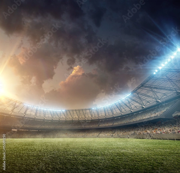 Obraz Stadion piłkarski z oświetleniem i zieloną trawą na zachodzie słońca