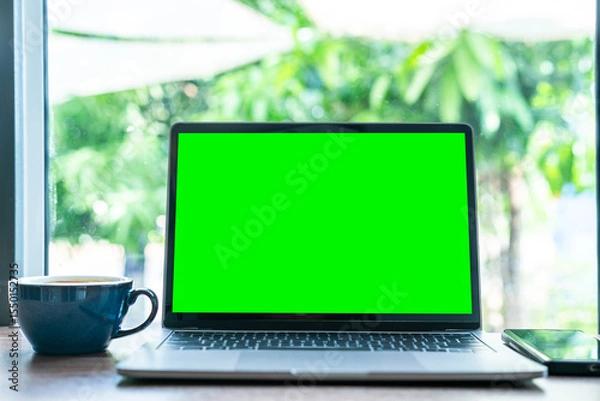 Obraz Mockup of laptop computer with empty screen with coffee cup and smartphone on table of the coffee shop background,Green screen
