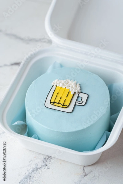 Fototapeta Small bento cake with blue cream cheese frosting decorated with a glass of foaming beer drawing in a gift box. Trendy cake as a gift for a beloved man